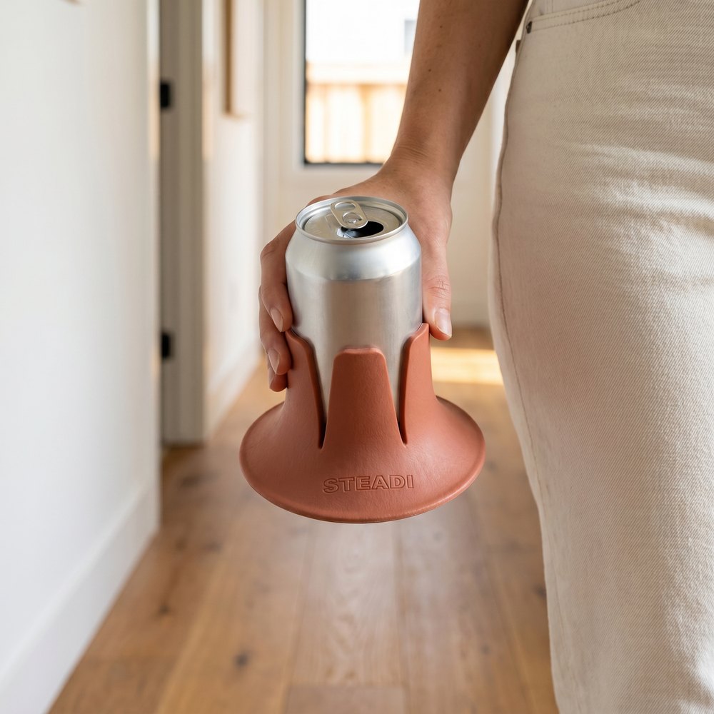 A hand sliding a can down into a charcoal Steadi so the fins take hold of the bottom inch.